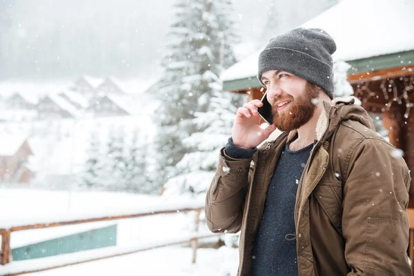 Glücklicher Mann, der im Winter draußen mit dem Handy telefoniert — Stockfoto