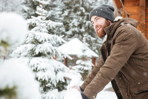 Homem feliz de pé e desfrutando de tempo nevado no resort de inverno — Fotografia de Stock