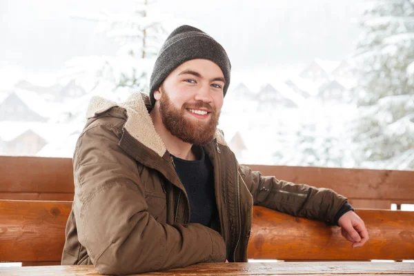 Fröhlicher Mann, der im Winter draußen sitzt — Stockfoto