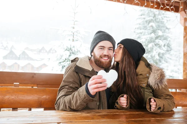 Пара поцелуев и держание сердца, сделанного из снега зимой — стоковое фото