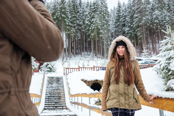 Усміхнена красива молода жінка стоїть і позує в зимовому лісі — стокове фото