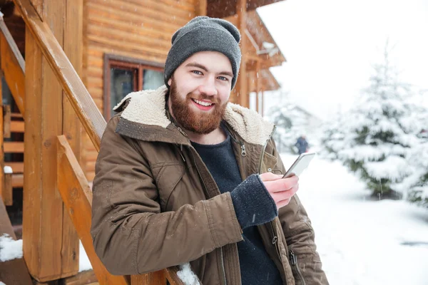 Fröhlicher Mann nutzt Smartphone im Winter im Freien — Stockfoto