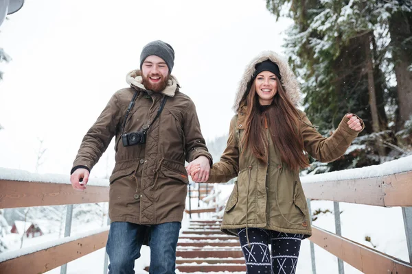 Пара тримає руки і бігає по сходах взимку — стокове фото