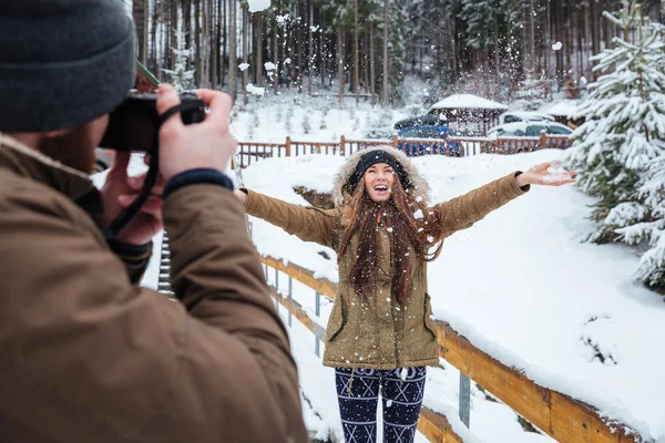 Мужской фотограф фотографирует счастливую женщину в зимнем лесу — стоковое фото