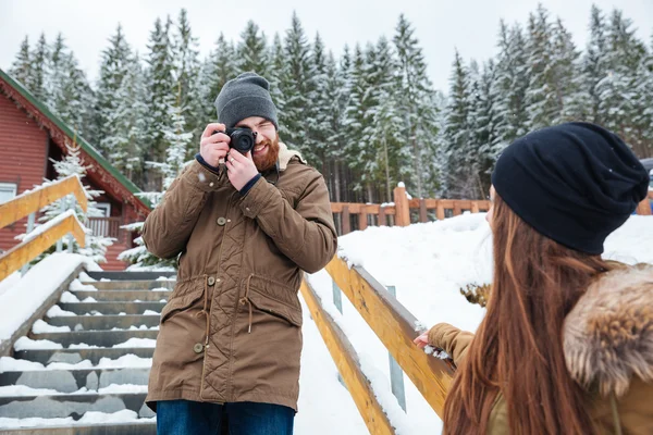 Улыбающийся фотограф фотографирует женщину на лестнице зимой — стоковое фото