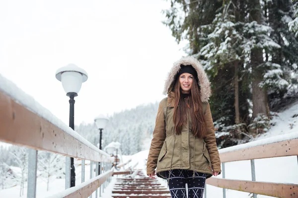 Улыбающаяся женщина, идущая по лестнице в зимнем горном курорте — стоковое фото