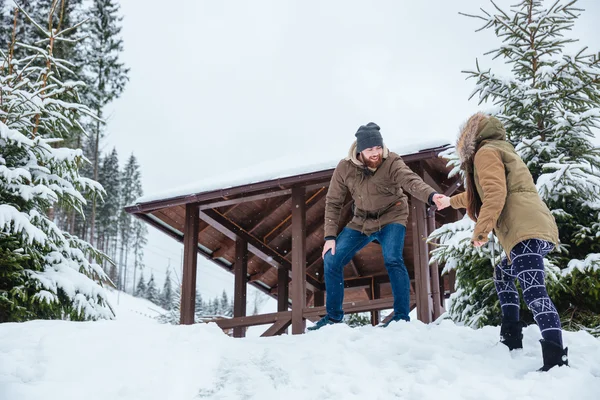 Hombre ayudando a su novia en caminar montañas en invierno — Foto de Stock