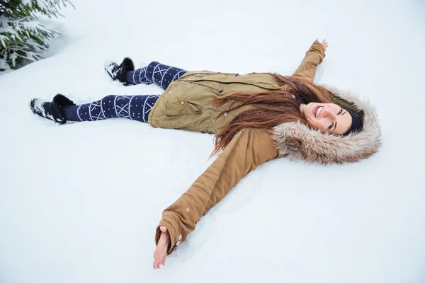 Mujer bonita alegre tumbada en la nieve en invierno —  Fotos de Stock