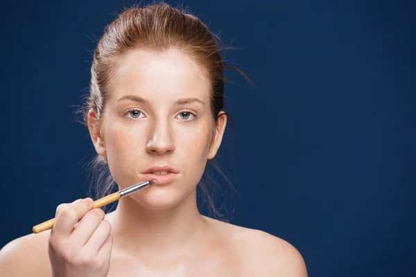 Kvinde anvender læbestift med en applikator - Stock-foto