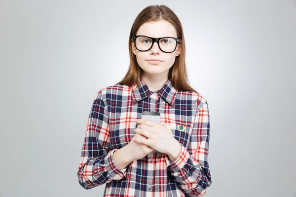 Allvarliga vacker tonårig flicka i glasögon snading och hålla smartphone — Stockfoto