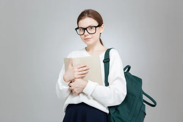 Adolescente chica en gafas con mochila de pie y la celebración de libro —  Fotos de Stock