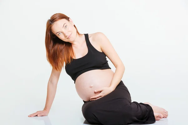 Mujer embarazada feliz sentada en el suelo — Foto de Stock