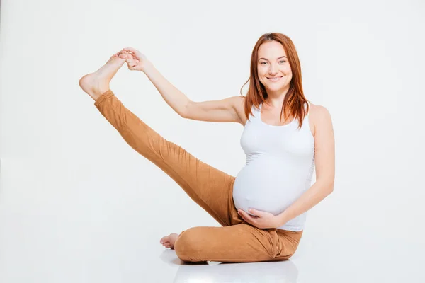 Усміхнена вагітна жінка розтягує ногу на плаву — стокове фото