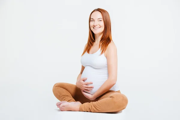 Щаслива вагітна жінка сидить на підлозі — стокове фото