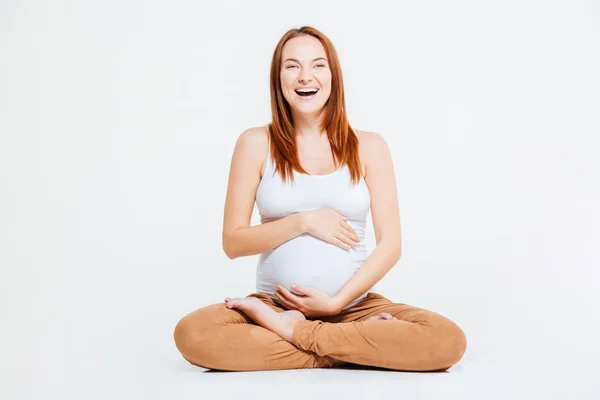 Сміється вагітна жінка сидить на підлозі — стокове фото