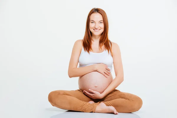 Leende gravid kvinna sitter på golvet — Stockfoto