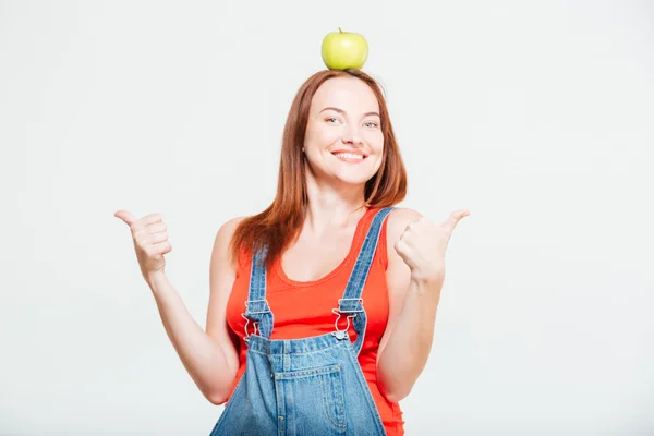 Těhotná žena s apple na hlavu ukazuje palec — Stock fotografie