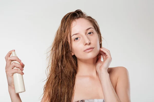Молодая женщина распыляет лак для волос — стоковое фото
