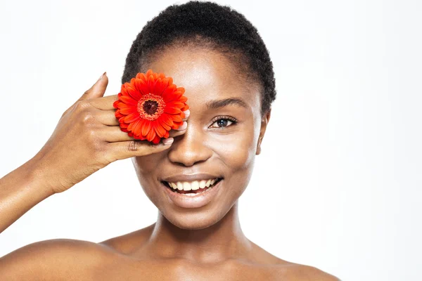 Sorridente afro americana donna che copre l'occhio con fiore — Foto Stock