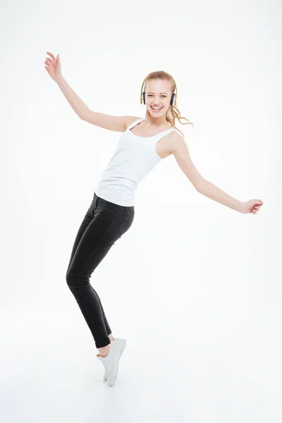 Cheerful woman in yellow headphones listening to music and dancing — Stock Photo, Image