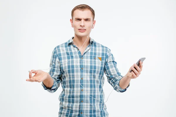 Unhappy irritated young man listening to music from smartphone — Stock Photo, Image