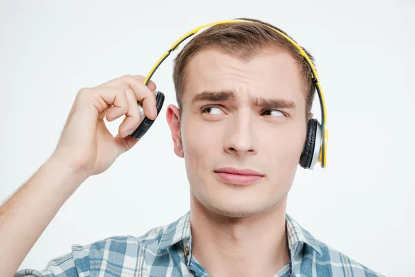 Jovem bonito infeliz tirando fones de ouvido — Fotografia de Stock