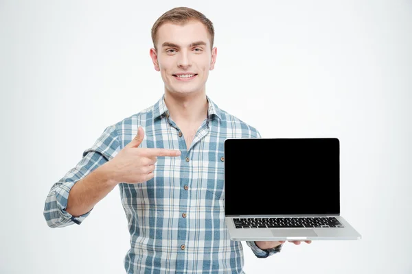 Улыбающийся мужчина держит пустой экран ноутбука и указывает на него — стоковое фото