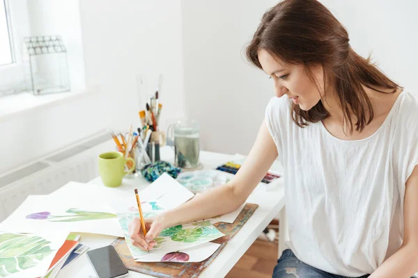 Vrouw kunstenaar tekenen aan de tafel in het atelier — Stockfoto