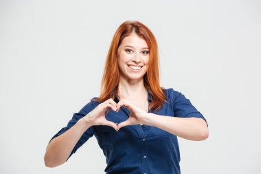 Neşeli güzel kızıl saçlı genç kadın elleriyle kalp yapma 