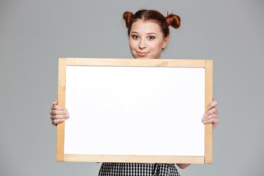 Gülümseyen güzel genç kadın boş beyaz tahta gösteren 