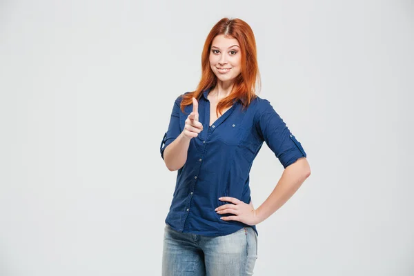 Happy pretty redhead young woman standing and pointing on you — Stockfoto