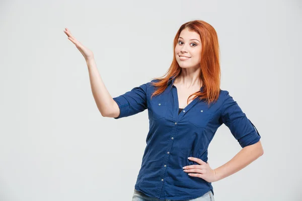 Cheerful pretty redhead young woman showing and presenting copyspace — Stockfoto