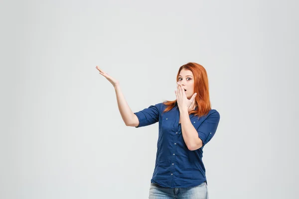Amazed woman covered mouth with hand and showing copyspace — Stockfoto