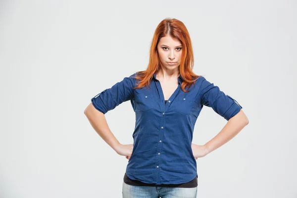 Frowning annoyed redhead young woman with hands on waist — Stock Photo, Image