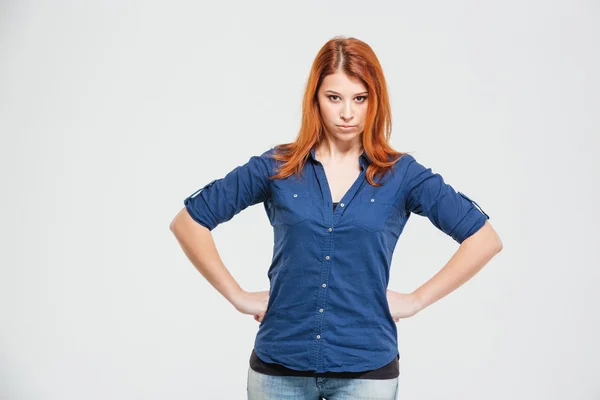 Frowning irritato rossa giovane donna con le mani in vita — Foto Stock