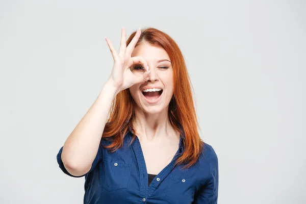 Feliz mujer excitada mirando a través de un agujero hecho de dedos —  Fotos de Stock
