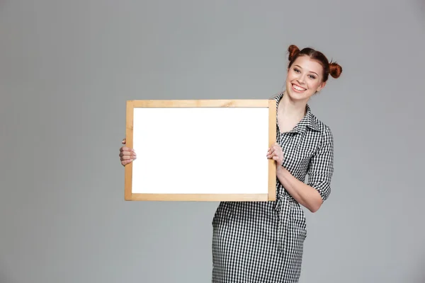 Χαρούμενη γοητευτική νεαρή γυναίκα στέκεται με λευκό πίνακα — Φωτογραφία Αρχείου