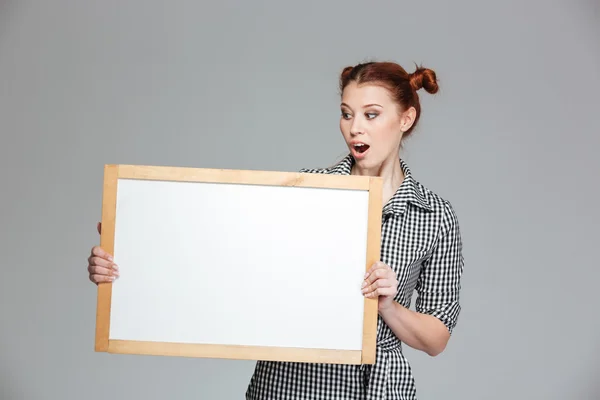 Amamzed cute woman holding and looking at blank whiteboard — Stock Photo, Image