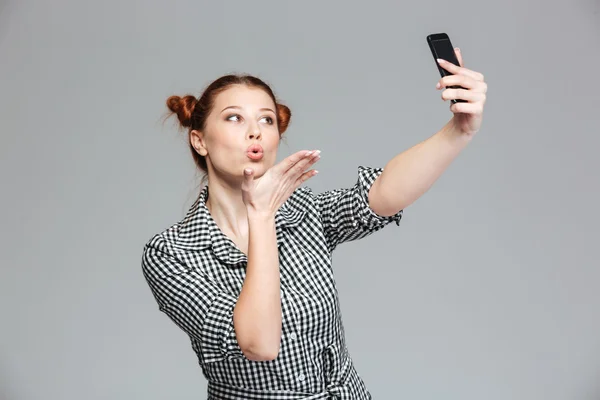 Hravý ženský, který posílá pusu a dělá si s mobilními telefony — Stock fotografie