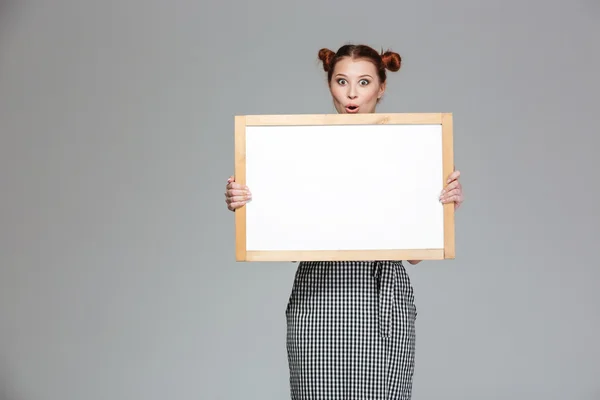 Jovem surpresa divertida segurando quadro branco em branco — Fotografia de Stock