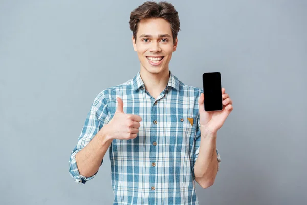 Hombre mostrando pantalla de teléfono inteligente en blanco y pulgar hacia arriba — Foto de Stock