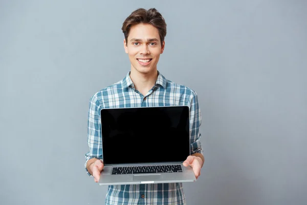 Lachende casual man lege laptopcomputer tonen — Stockfoto