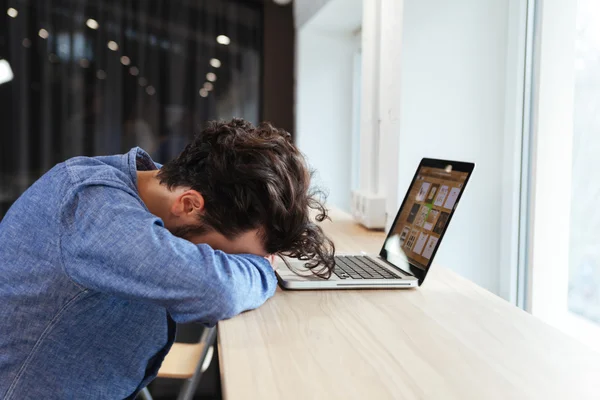 Affärsman sover vid bordet med bärbar dator — Stockfoto