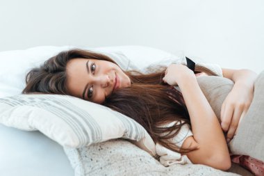 Yatakta yatan ve yastık sarılma gülümseyen kadın 