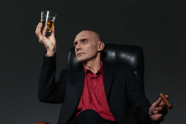 Empresario con vaso de whisky y cigarro sentado en silla —  Fotos de Stock
