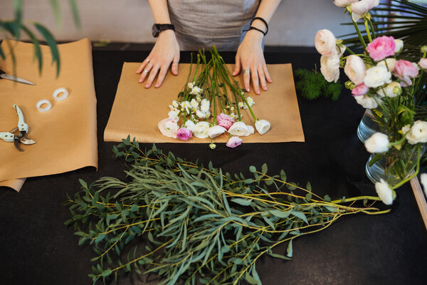 Female florist designing and creating flower bouquet on black table