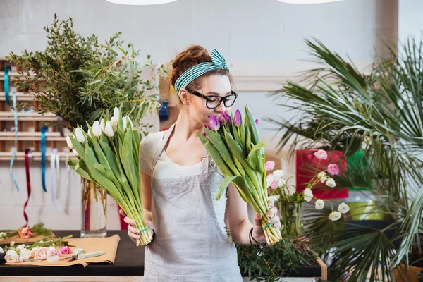 Gelukkige vrouw bloemist ruiken tulpen in de bloemenwinkel — Stockfoto