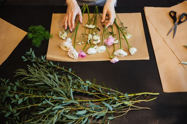 Handen van vrouwelijke bloemist boeket op zwarte tafel maken — Stockfoto