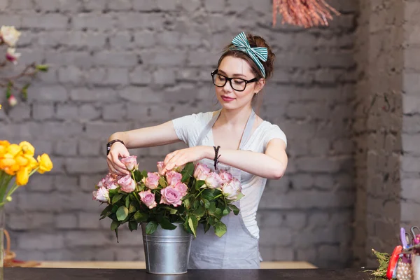 Hermosa florista mujer arreglando rosas en cubo —  Fotos de Stock