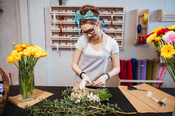 Lachende vrouw bloemist permanent en het maken van boeket in bloemenwinkel — Stockfoto